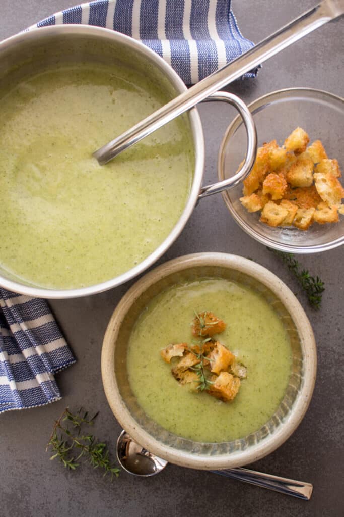 Broccoli soup in a bowl and in a silver pot.