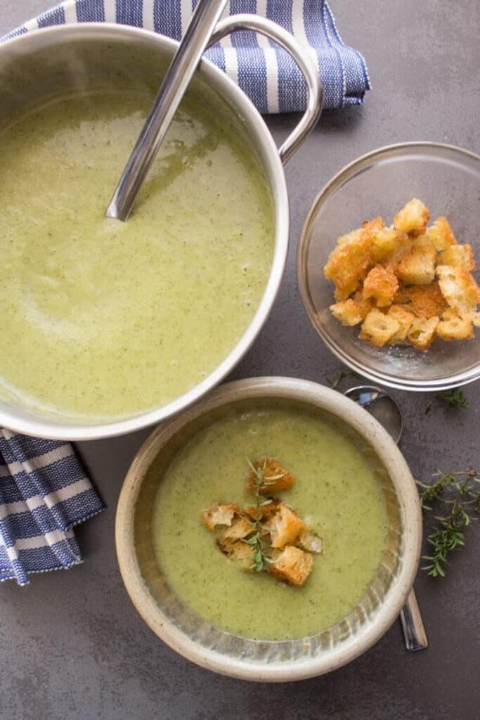 Soup in a pot and in a bowl with croutons on top.