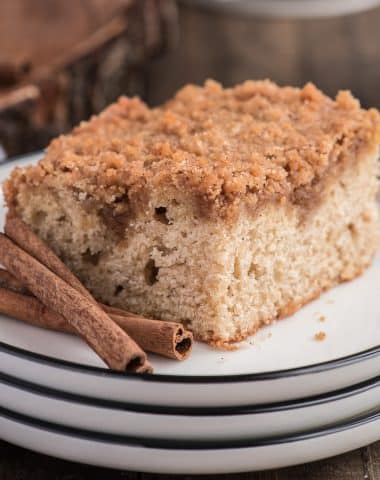 A slice of cinnamon crumb cake on a white plate.