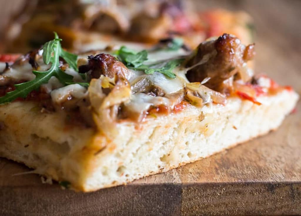 A slice of mushroom pizza on a wooden board.