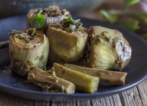 cooked roman artichokes on a black plate